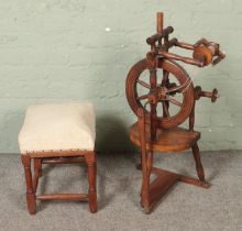 A vintage wooden spinning wheel along with small cushioned stool.