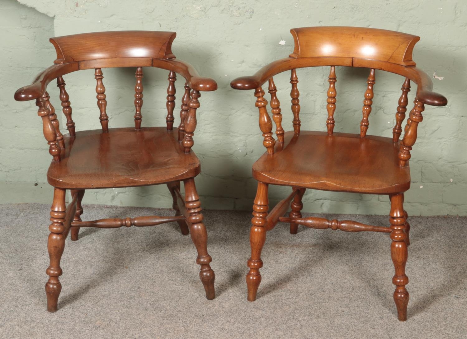 A near pair of beech and elm smokers bow armchairs.