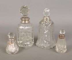 Four silver collared perfume bottles to include bell shaped example with floral decoration.