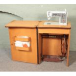 A vintage Singer sewing machine cabinet along with small quantity of haberdashery. Machine model