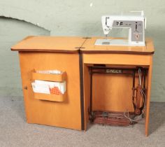 A vintage Singer sewing machine cabinet along with small quantity of haberdashery. Machine model