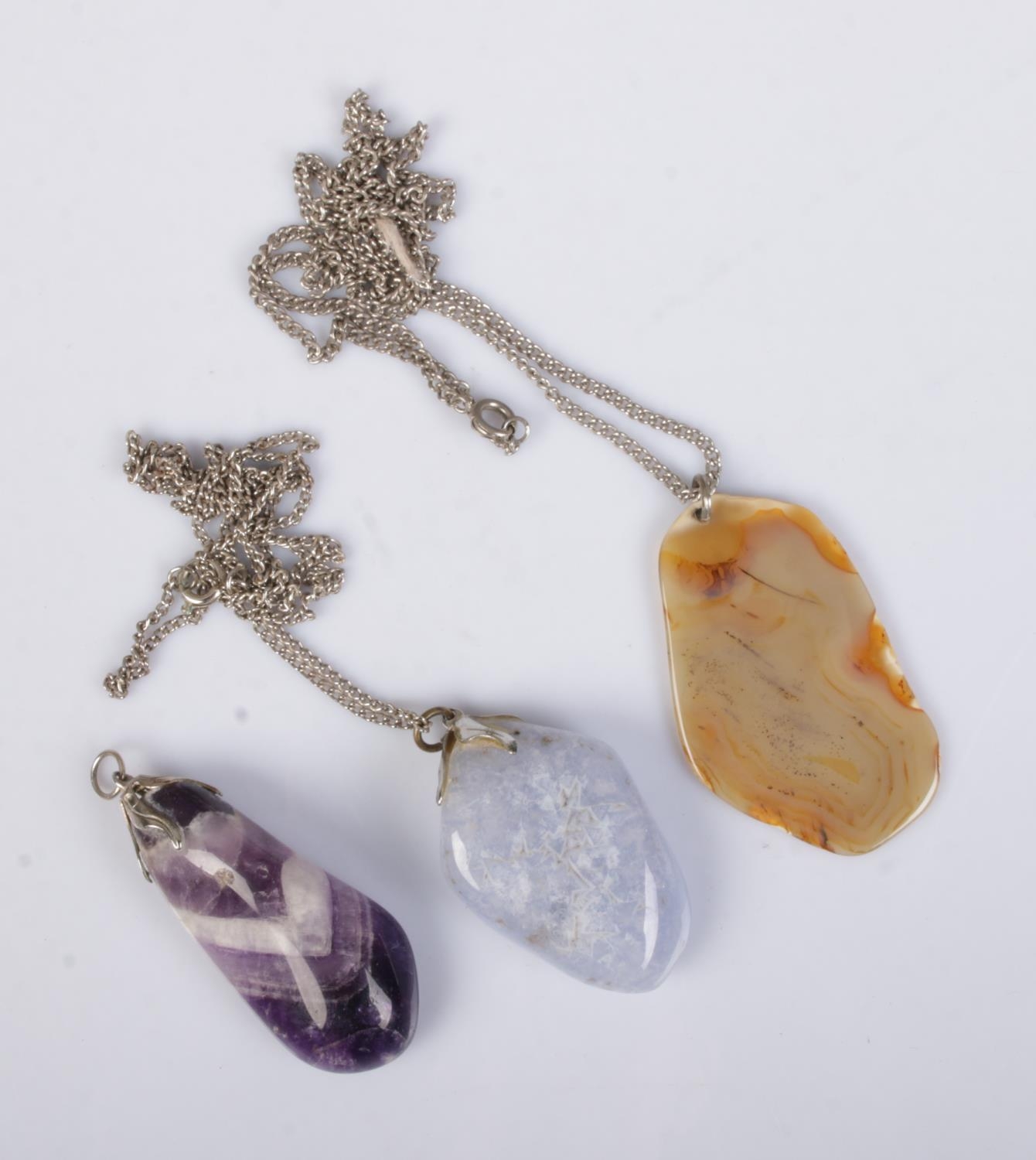 Three polished gemstones pendants to include Blue John and agate examples. Two on white metal