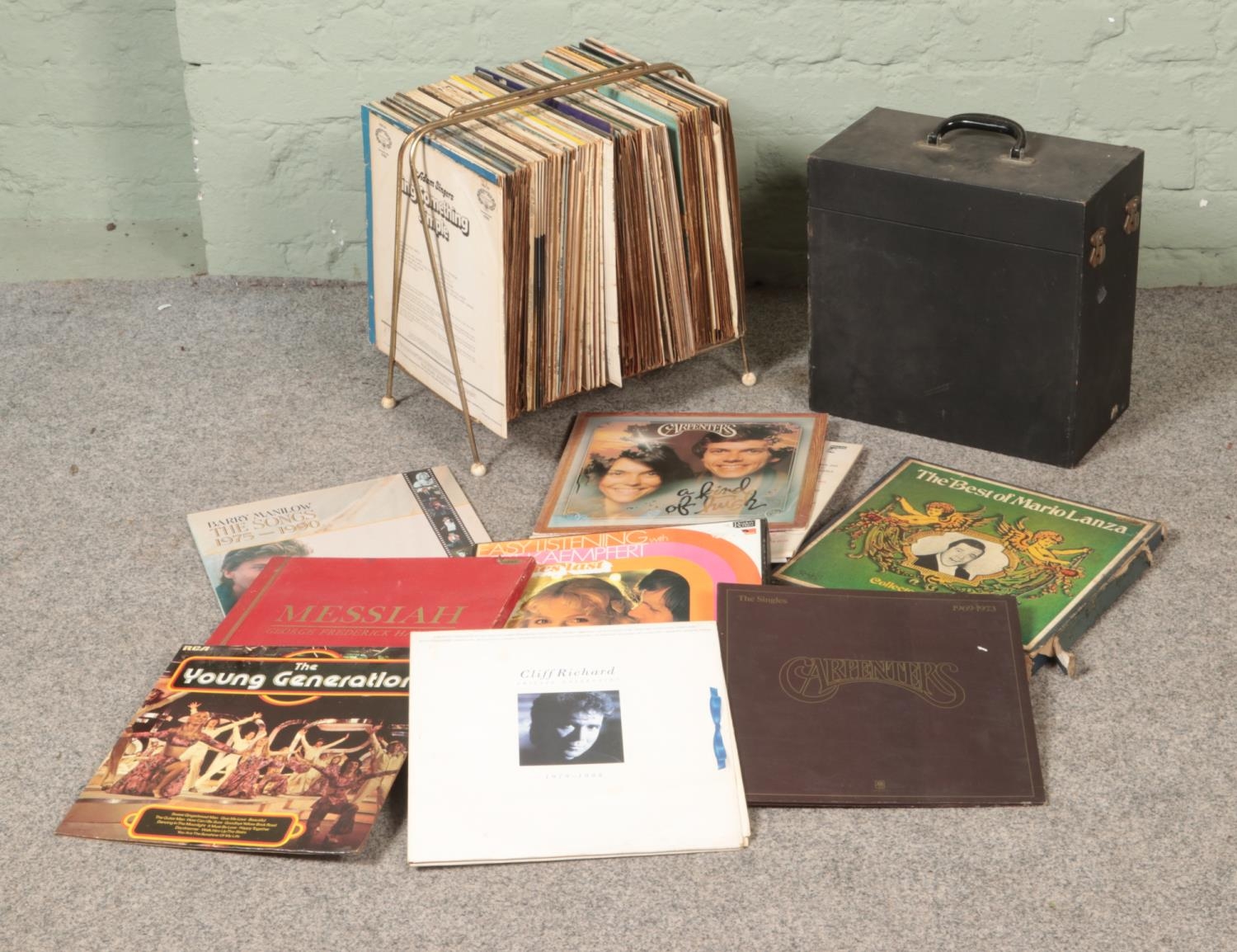 A collection of vinyl records in a vintage rack and travel case including Carpenters, Mario