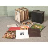 A collection of vinyl records in a vintage rack and travel case including Carpenters, Mario