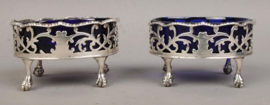 A near pair of Georgian silver salts, with Bristol blue glass liners, raised on ball and claw