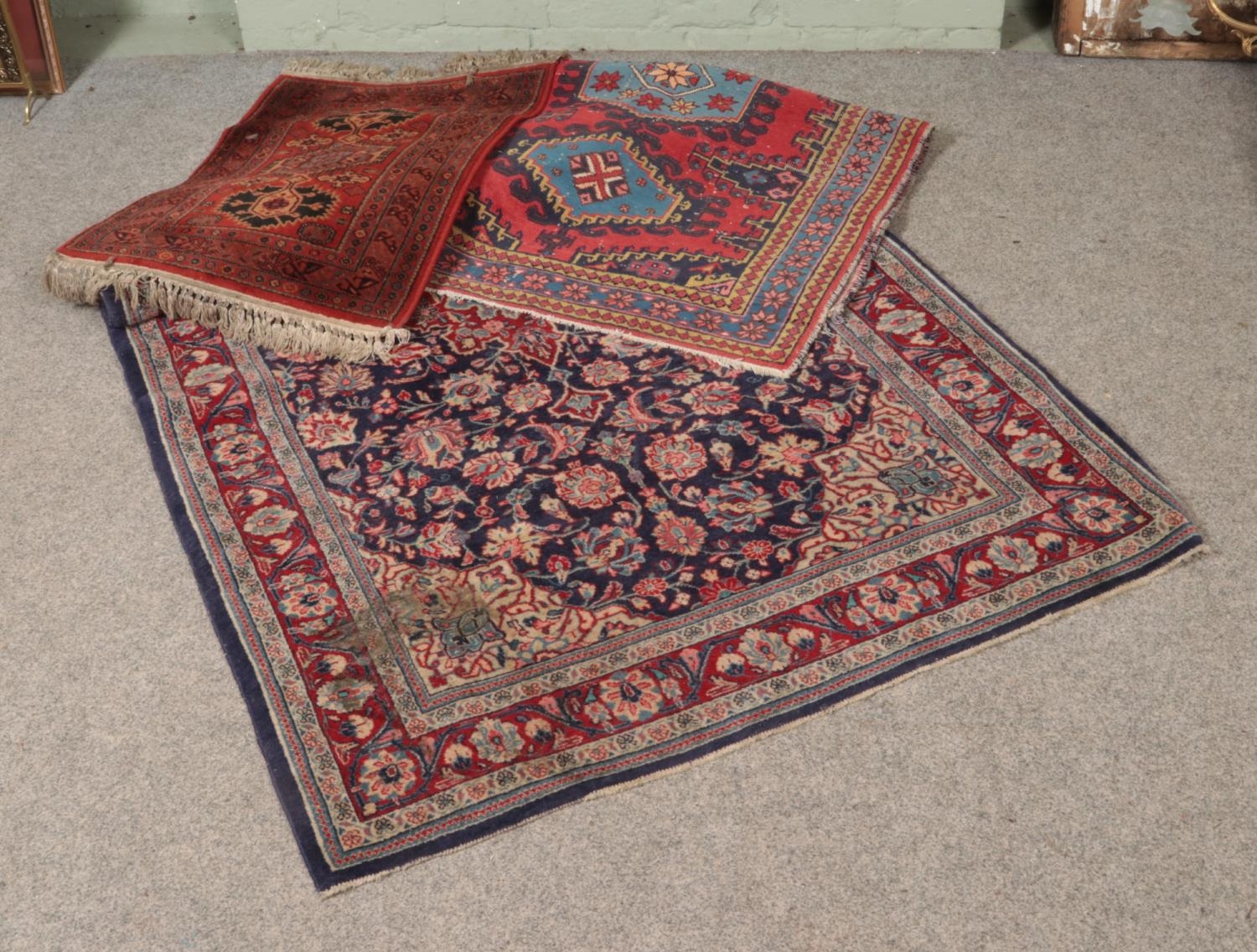 A collection three of rugs including red and blue floral design with central medallion.