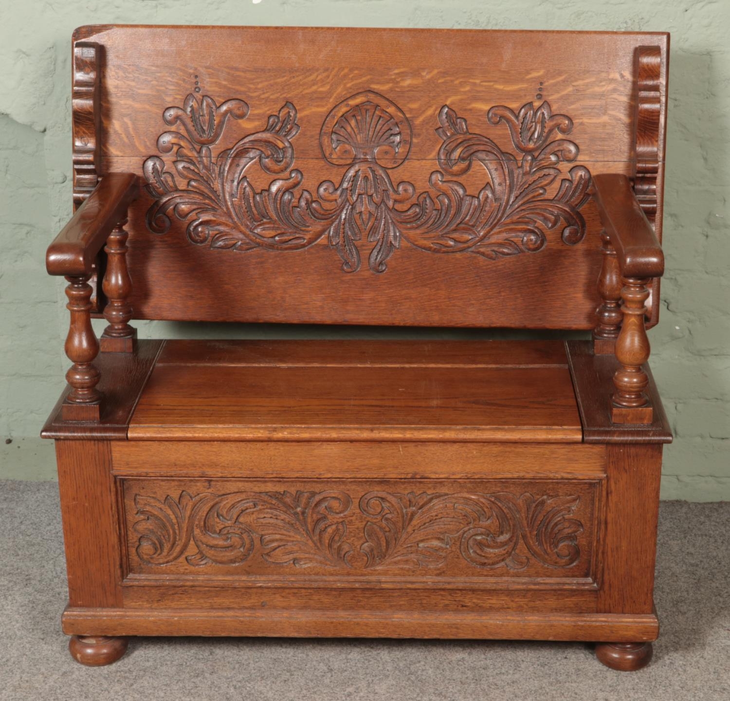 A carved oak monks bench, with detailing to back rest and front. Featuring folding top and under