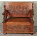 A carved oak monks bench, with detailing to back rest and front. Featuring folding top and under