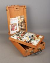 A wooden artist's box, with hinged top and folding easel back. Containing a collection of paints,