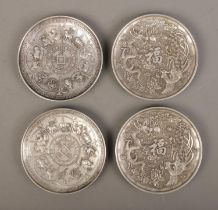 A set of four decorative Oriental white metal coasters featuring dragon and Phoenix motifs along