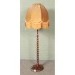A barley twist standard lamp with fringed velvet shade.
