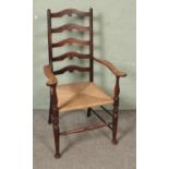 An early 20th century arts and crafts style ladder back elbow chair