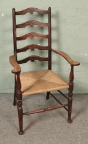 An early 20th century arts and crafts style ladder back elbow chair