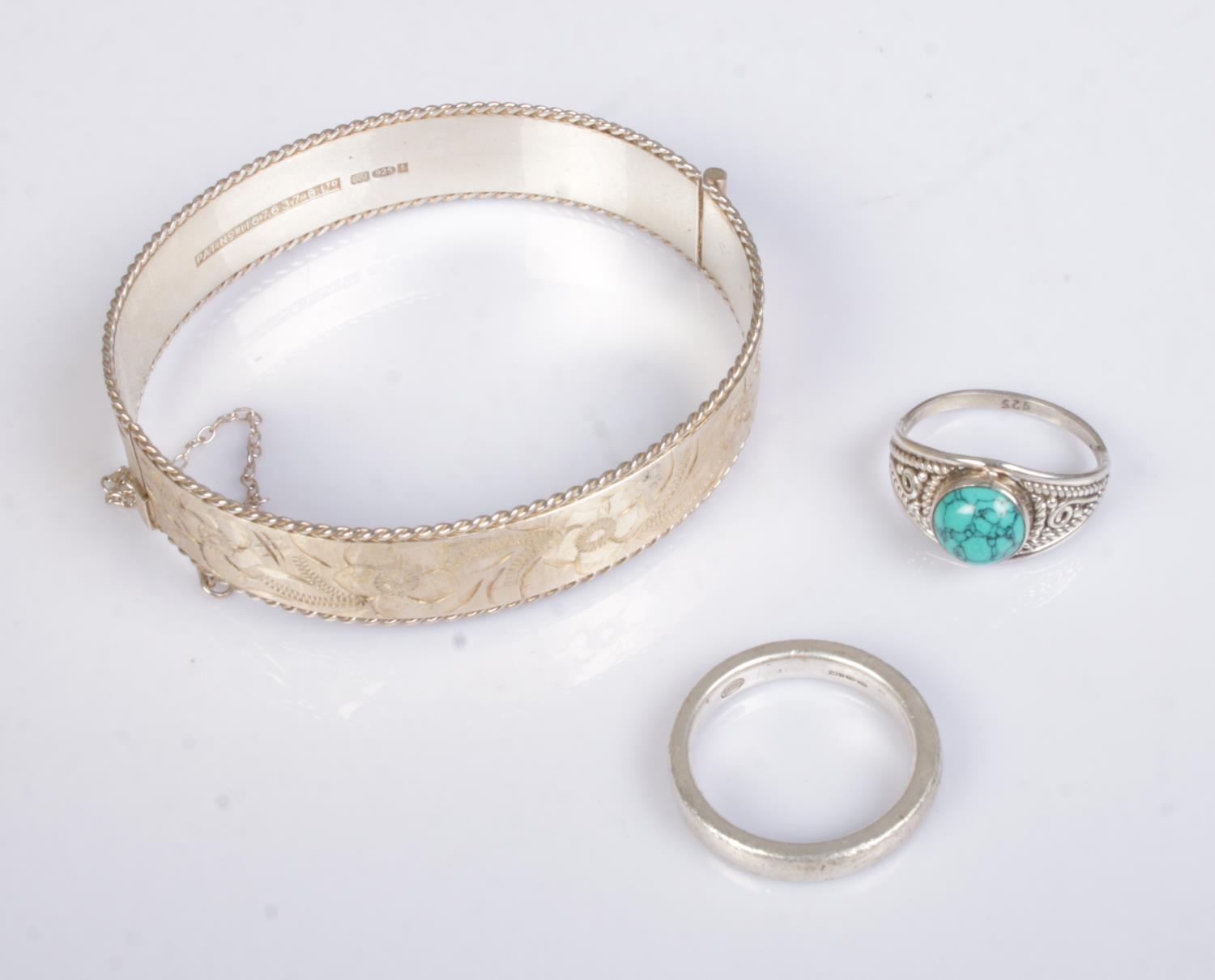 A small collection of silver jewellery to include floral engraved bangle and two rings. Total weight