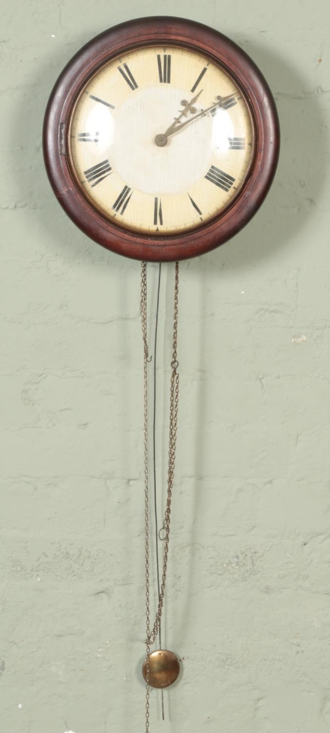 A mahogany postman's alarm clock with roman numeral dial with pendulum. Does not include weights