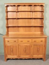 An Ercol light oak Welsh dresser, with cupboard doors and drawers to the base and plate rack top.