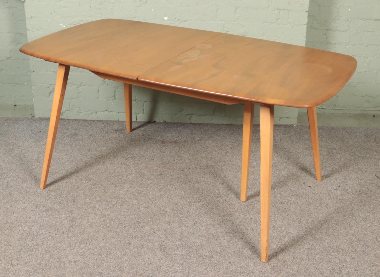An Ercol 'Grand Windsor' light oak and ash extending dining table, with hinged additional leaf,