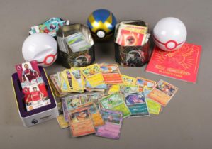 Two tins of Pokemon trading cards including holographic and reverse holographic holo examples,
