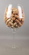 A large wine glass with contents of corks. Height of glass 49.5cm.