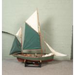 A large remote control model fishing boat with green and white cloth sails on display stand. Approx.