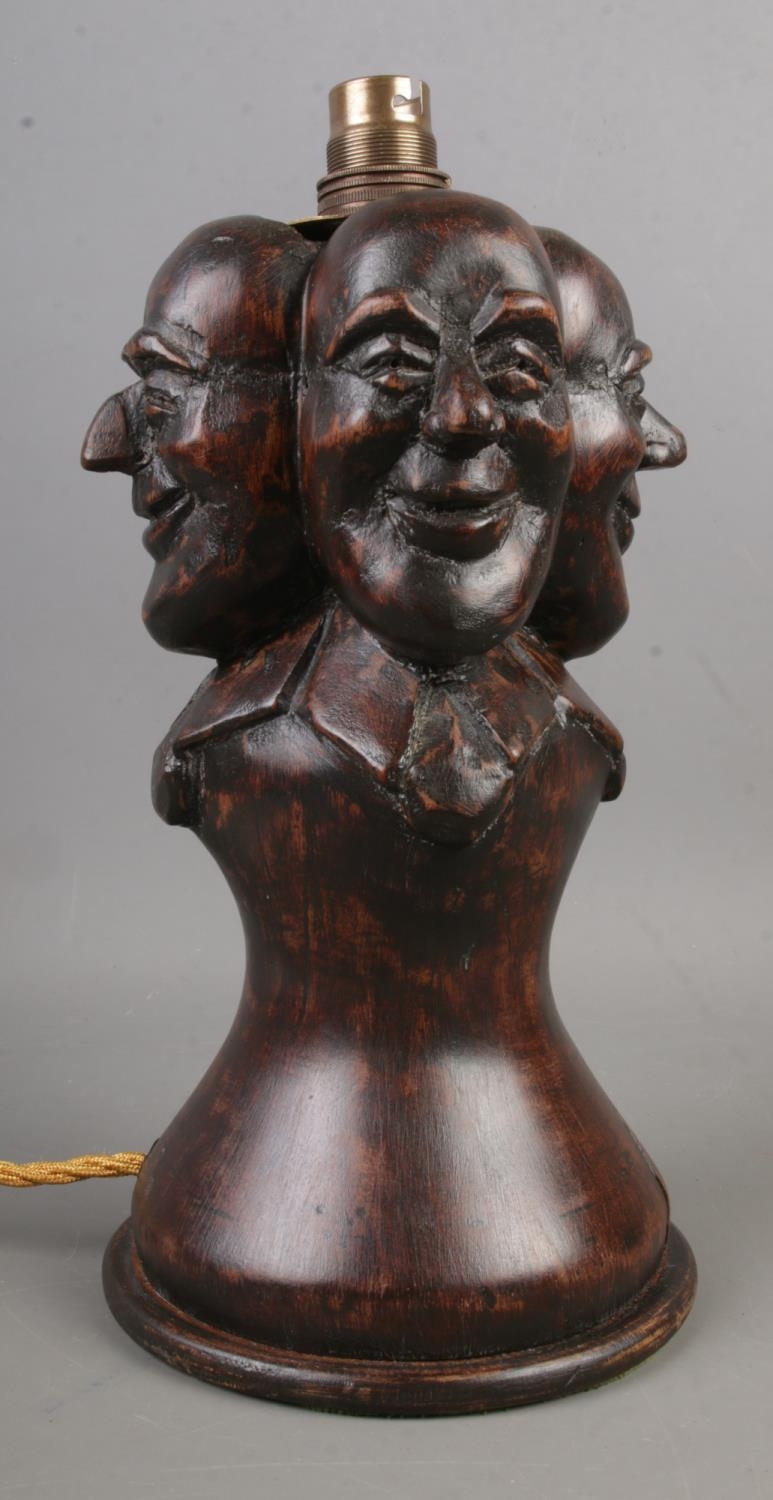 A wooden Folk Art table lamp, with four mask decoration. (Height approximately 29cm).