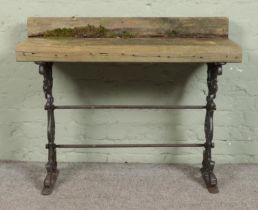 A garden table composed of sleepers, on cast iron base. Height: 85cm, Width: 107cm, Depth: 43cm.