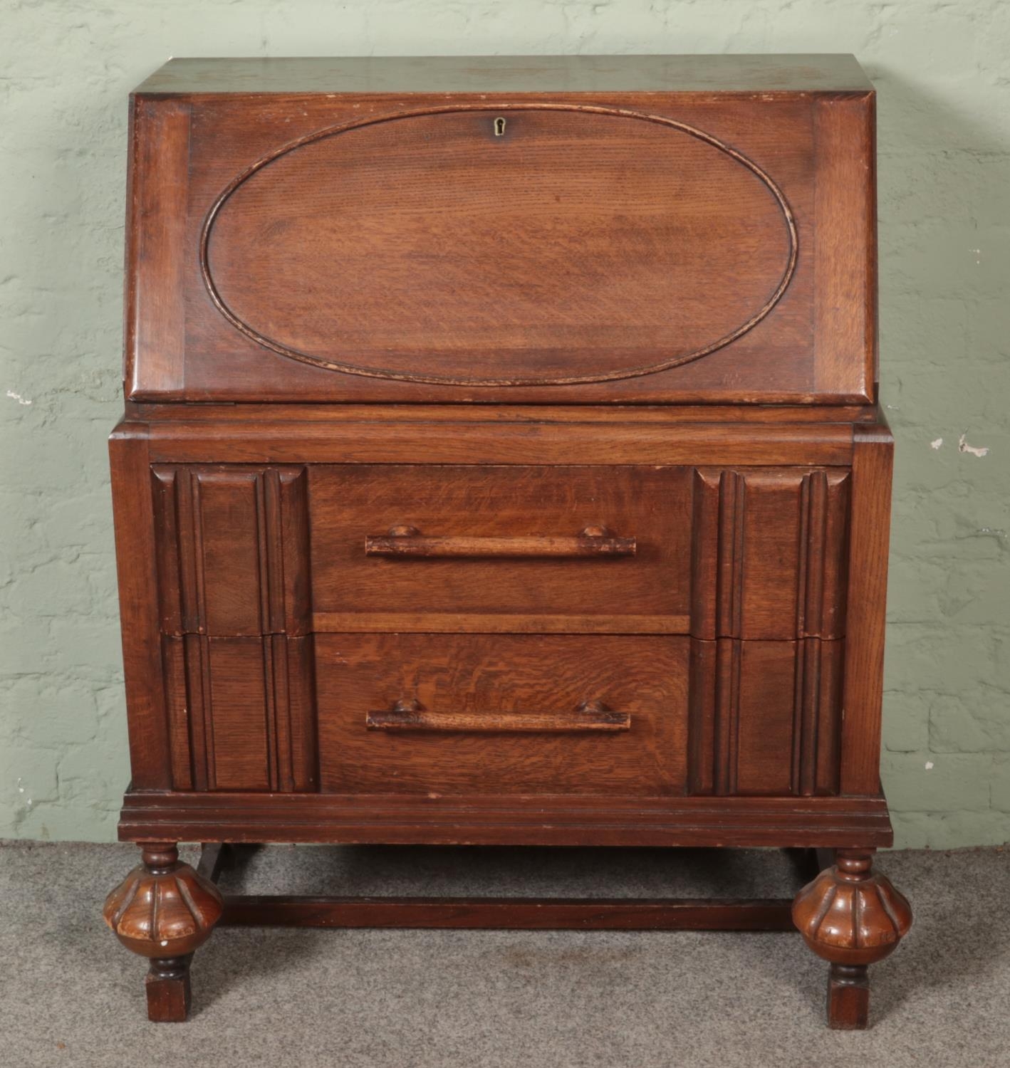 An oak linen fold style bureau with large bar pull handles