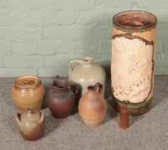 A box of assorted stoneware water jugs, including salt glazed examples, along with an umbrella/stick