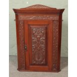 A heavily carved oak corner cabinet