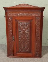 A heavily carved oak corner cabinet