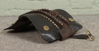 A vintage leather saddle, with studded and hooped detailing. Signs of worm to the wooden frame