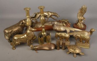 A collection of brassware pieces including candlesticks, miniature miners lamps, small vases, dog