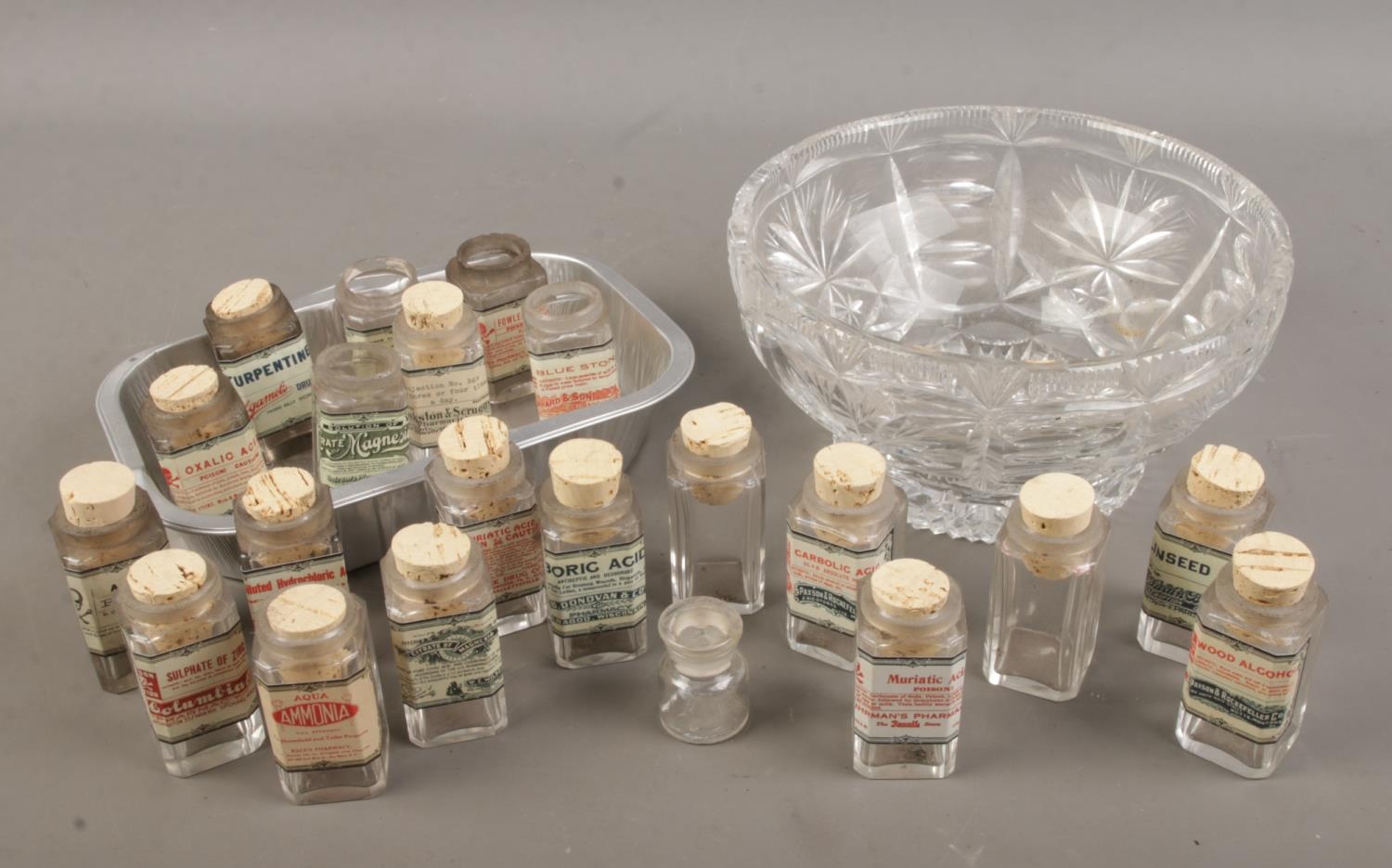 A cut glass bowl and tray with contents of reproduction acid/poison bottles.
