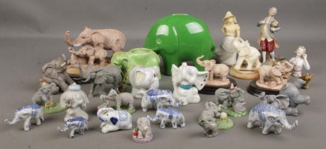 A large collection of various elephant figures including large green elephant piggy bank, small blue