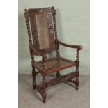 A carved Victorian oak elbow chair with bergere seat and back raised on barleytwist supports.
