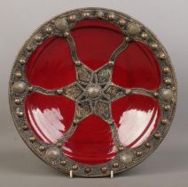 A 20th century Moroccan glazed terracotta dish with metal mounts and adorned with Moroccan coins.