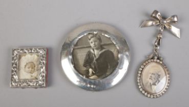 A collection of three small silver picture frames including brooch example.