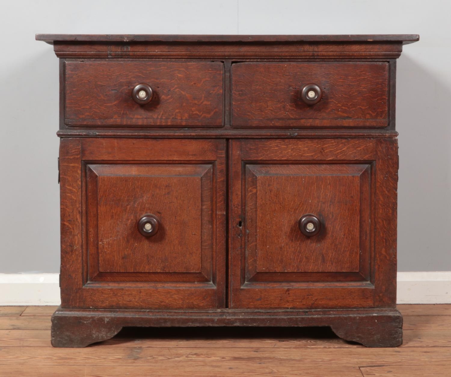 A Georgian oak sideboard, having two drawers and cupboard base. Right hand side door loose.