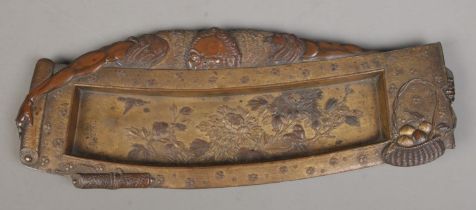 A Japanese Meiji period bronzed pen tray formed as a scholar holding a scroll. Bearing character