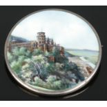 A continental silver and enamel brooch decorated with a landscape scene and castle. Stamped 800 to