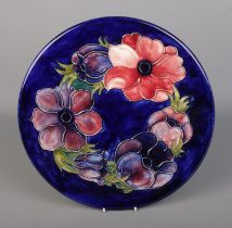 A Moorcroft pottery charger with dark blue ground base decorated in the Anemone pattern. Approx.
