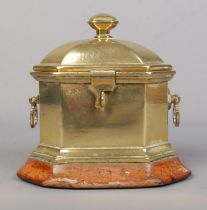 A Georgian brass tobacco box of sarcophagus form, raised on wooden plinth. Height 14cm.