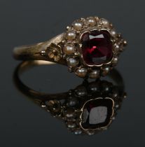 An antique 15ct gold garnet and seed pearl halo cluster ring. Having floral shoulders. Size L 1/2.