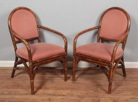 A pair of bamboo elbow chairs/carvers with upholstered seat and back.