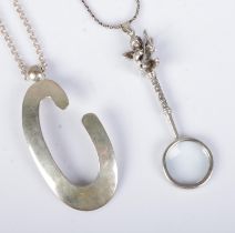 Two silver pendants on chains to include large letter C and small magnifying glass featuring harp