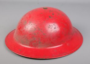 A World War Two civil defence/home front red painted steel helmet.