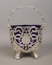 A Victorian silver pierced basket with swing handle and Bristol blue glass liner. Assayed London