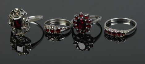 Four silver rings each set with garnets to include cluster and five stone example. Total weight 11.