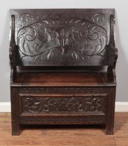 A carved oak monks bench with heraldic shield to back rest. Height to top of seat back 99cm, Width