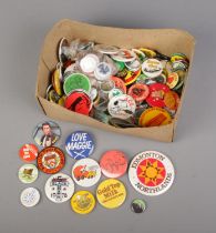 A box of assorted pin badges to include music, festival and advertisement examples.
